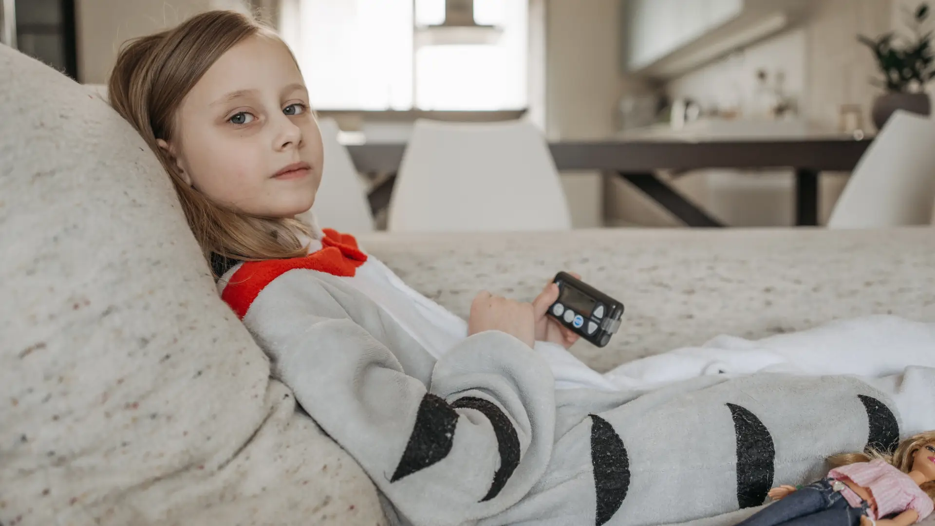 Junges Mädchen liegt mit einem Blutzuckermessgerät auf der Couch
