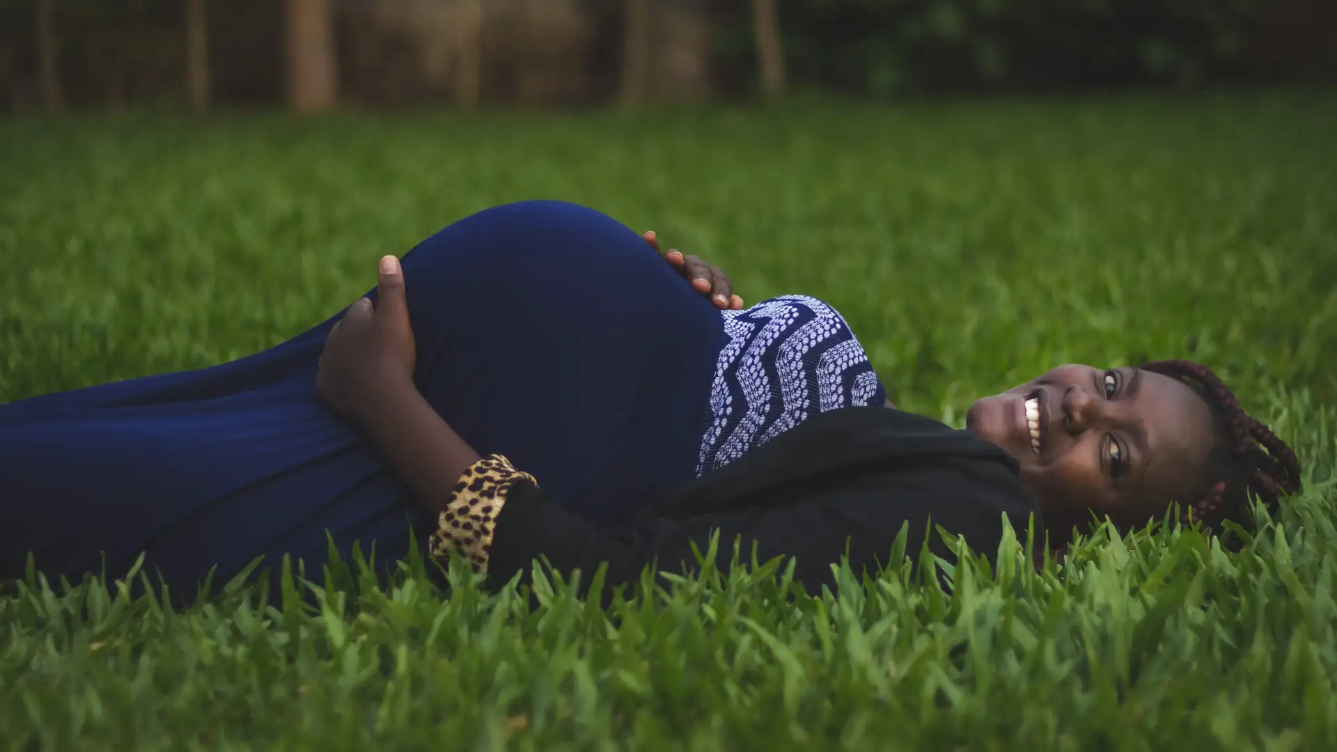 Schwangere dunkelhäutige Frau liegt auf dem Rasen