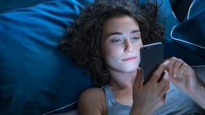 Ein Mädchen liegt wach im Bett mit ihrem Handy in der Hand.